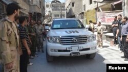 Binh sĩ thuộc Quân đội Syria Tự do vây quanh đoàn xe của các thanh sát viên LHQ đến điều tra về vấn đề vũ khí hóa học ở ngoại ô Zamalka, ngày 28/8/2013.