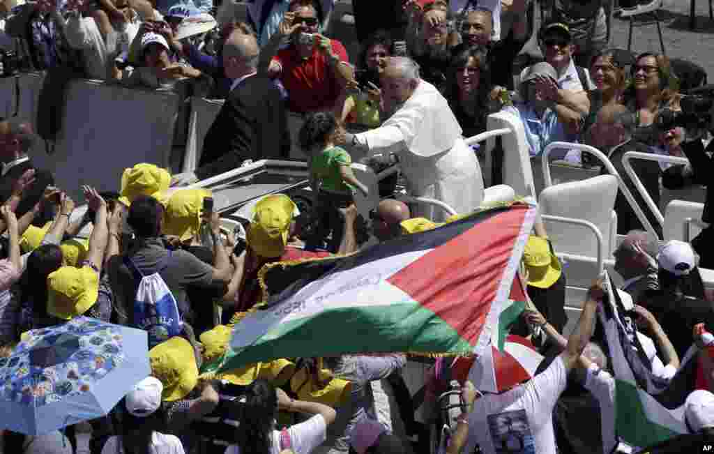Pope Francis greets a child in St. Peter's Square at the Vatican, May 17, 2015.