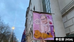 港人Moses Ng举起讽刺习近平和工党首相的漫画,表达对英国工党政府对华政策的失望。(李伯安/美国之音)