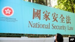 资料照：一名妇女走过香港街头宣传港版国安法的广告牌。（2020年6月30日）