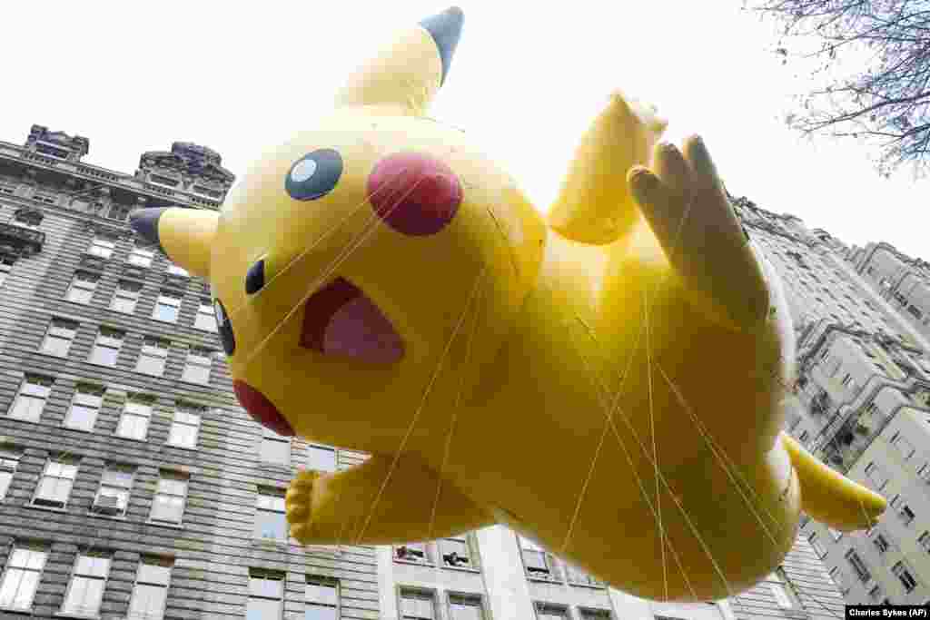 纽约梅西第89届感恩节大游行中,人们牵着《宝可梦》游戏中皮卡丘(The Pokemon character Pikachu)形状的气球(2015年11月26日)