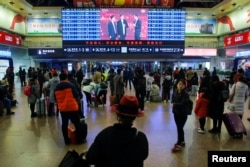 资料照:人们在北京火车站等车期间观看大屏幕播放的春晚。(2018年1月15日)