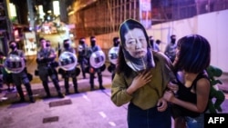 资料照:一名蒙面抗议者站在香港防暴警察前。(2019年10月31日)