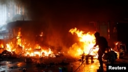 在香港理工大学学生与警察的冲突中一名抗议者试图浇灭火焰。(2019年11月18日)