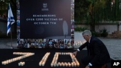 Seorang staf menyalakan lilin di kedutaan Israel di Beijing, untuk mengenang para korban pada peringatan satu tahun serangan Hamas terhadap Israel, Senin, 7 Oktober 2024. (Ng Han Guan/AP)