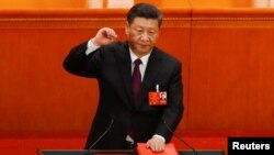 习近平左手抚按宪法,右手举拳,宣誓就任。(2018年3月17日路透社)