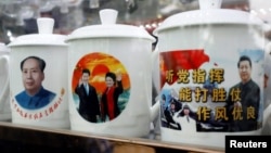 2017年10月21日,在北京举行的中共第十九届全国代表大会期间,北京一家商店展示的带有中国前国家主席毛泽东和中国国家主席习近平形象的纪念品水杯。一个杯子上有红日升起的背景形象,一个杯子上有口号“听党指挥,能打胜仗,作风优良”。