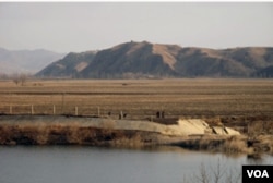 在田间劳作的朝鲜妇女以及山上的了望塔