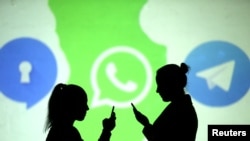 手机使用者站在加密通讯平台Telegram的标识前。加密通讯平台Telegram的标识是一只纸飞机。(2018年3月28日资料照片)