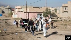 Người dân lánh chiến sự giữa quân đội Iraq và những kẻ chủ chiến Nhà nước Hồi giáo đi qua một ngõ ở quận Gogjali, ờ vùng ngoại ô phía đông Mosul, Iraq, ngày 5 tháng 10, 2016.