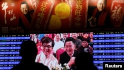 资料照:人们在北京火车站等车期间观看大屏幕播放的春晚。(2018年1月15日)