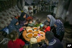 Fatima Al-Absi, kiri, berbuka puasa bersama putri dan cucunya pada hari pertama Ramadan di apartemen mereka yang rusak di Jabaliya, Jalur Gaza utara, 1 Maret 2025. (Foto: AP)