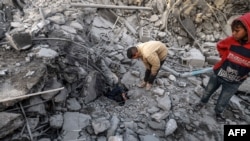 以色列轰炸加沙南部拉法后，巴勒斯坦人在一座清真寺和建筑的废墟上。（2024年1月24日）