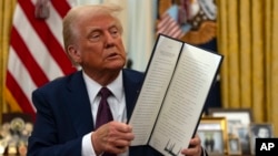 资料照:美国总统特朗普在白宫手举一份他刚刚签署的行政令。(2025年1月23日)