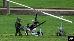 Một thành viên đội gỡ bom kiểm tra chiếc máy bay trực thăng nhỏ sau khi một người đàn ông hạ cánh trong khuôn viên bãi cỏ phía tây của Điện Capitol, Washington, 15/4/2015.