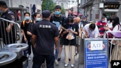 在北京的一条旅游购物街,人们用智能手机向保安出示健康码(2021年8月3日)。