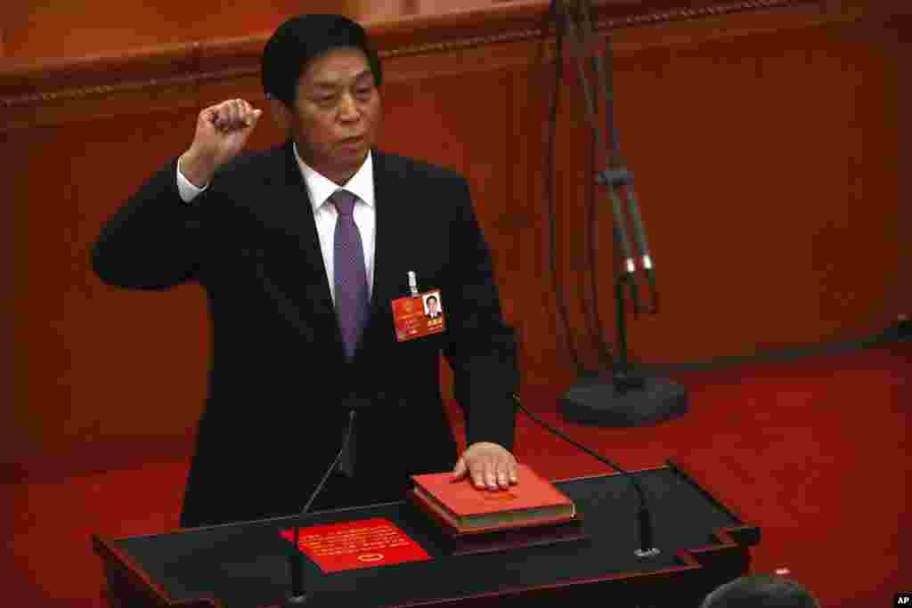 新当选的中国人大委员长栗战书2018年3月17日在全国人大全体会议上手按宪法,宣誓就职。