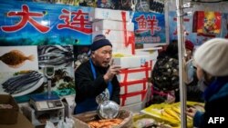 资料照:北京一家海鲜市场的小贩正在向顾客兜售水产品。(2020年1月15日)