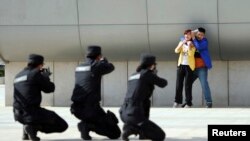 2014年五月7日,中国郑州警方在火车站举行反恐演习。武装警察举枪瞄准一个劫持妇女的恐怖分子的扮演者