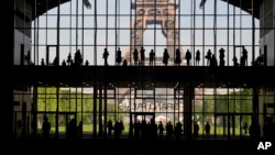 在法国巴黎,游客们聚集在一起参观以埃菲尔铁塔为背景的巴黎大皇宫(Grand Palais Ephemere)。