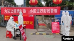 身穿防护服的工作人员在武汉一个住宅小区的入口设立登记与体温测量的检查点。(2020年2月13日)