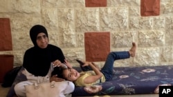 逃离以色列空袭后，一名流离失所的妇女和她的女儿坐在黎巴嫩贝鲁特南部小镇的联合国巴勒斯坦难民机构。(美联社：2024年10月4日)