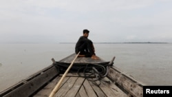 资料照片:在印度和孟加拉国边界附近的布拉马普特拉河面上,一名男子坐在一条船上。(2018年8月4日)