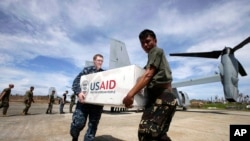 菲律宾和美国军人携手把美国救灾物资卸下美国鱼鹰军机。(2013年11月20日)