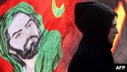 Một người Hồi giáo Shia Iraq đi ngang qua hình ảnh của Thánh Hussein.