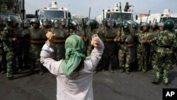 一名维吾尔族妇女在一群中国武警面前要求归还她的族人。(2009年7月7日)