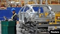 中国汽车制造商协会表示,由于冠状病毒的流行,今年上半年中国的汽车销量可能下滑10%以上。图为2012年4月20日,在重庆市福特汽车制造厂的生产线上,一名员工在旁使用笔记本电脑。(路透社资料照)
