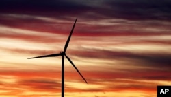 2023年11月29日,美国总统拜登访问全球最大的风塔制造商 CS Wind 之前,在科罗拉多州普韦布洛拍摄的太阳升起和风车的照片。(美联社照片)