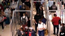 为了防止新冠病毒的传播,达拉斯机场在安检排队处设置了玻璃隔板,旅客们也佩戴了口罩。(2021年12月31日)