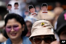 Para pendukung mengenakan aksesoris kepala bergambar capres Prabowo Subianto dan pasangannya Gibran Rakabuming Raka, saat pasangan tersebut mendaftarkan pencalonan mereka pada pemilu 2024 di gedung KPU, Jakarta, 25 Oktober 2023. (AP/Achmad Ibrahim)