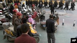 2017年11月5日,中部新疆地区的喀什市居民观看一队保安人员。