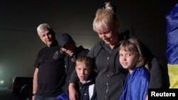 Світлана Рябцева обіймає своїх дітей Ангеліну та Олександра, яких торік у вересні незаконно вивезли до Росії з окупованого тоді Куп'янська, а на початку вересня цього року дітей вдалось повернути до України, Волинь. 3 вересня 2023. REUTERS/Andriy Perun