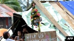 临时栖身处里的菲律宾儿童。简易圣诞树上挂的牌子上写着:美国帮忙 圣诞快乐