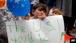 六岁男孩舒阿·里奇跟着母亲参加在凯文·约德众议员在堪萨斯州欧芙兰帕克的办公室外的机会,抗议政府的移民政策。(2018年6月22日)