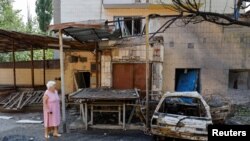 2024年7月22日,在俄罗斯控制的乌克兰顿涅茨克地区,一名妇女走在最近发生的炮击现场。由俄罗斯扶立的地方当局称炮击是乌克兰方面实施的军事打击。(路透社照片)