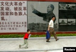 资料照:广东省汕头市举办文革展览,参观者走过的一幅毛泽东在文革期间的画像。(2007年4月25日)