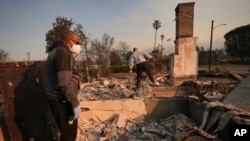 资料照片:肯尼斯·斯诺登(左)与他的兄弟罗尼一起勘察2025年1月10日在加利福尼亚州阿尔塔迪纳发生的伊顿火灾后他家灾后损失情况。