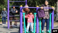 中国第七次人口普查数据显示,中国人口“低速增长”,趋于老化。图为北京天坛公园里的老年人和他们的独生子女的孙辈在锻炼身体。(法新社2011年10月25日资料照)