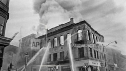 资料照片 - 消防员将水流引向新泽西州纽瓦克王子街和法院街拐角的一座着火的建筑,在那里持续了四天的致命暴力和抢劫后来被称为纽瓦克骚乱。(1967年7月15日)(美联社照片/马蒂·莱德汉德,档案)