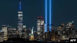 Patung Liberty di New York berhiaskan sinar lampu dalam peringatan 11 September 2021. (ROBERTO SCHMIDT / AFP)