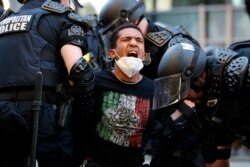 A demonstrator is taken into custody by police after a curfew took effect during a protest over the death of George Floyd, Monday, June 1, 2020, near the White House in Washington.