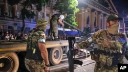 资料照:瓦格纳雇佣军士兵在俄罗斯罗斯托夫的街道上往一辆拖运车上装载坦克。(2023年6月24日)