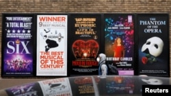 纽约曼哈顿百老汇剧院区的广告旁走过一名戴着口罩的男子。(2020年3月12日)