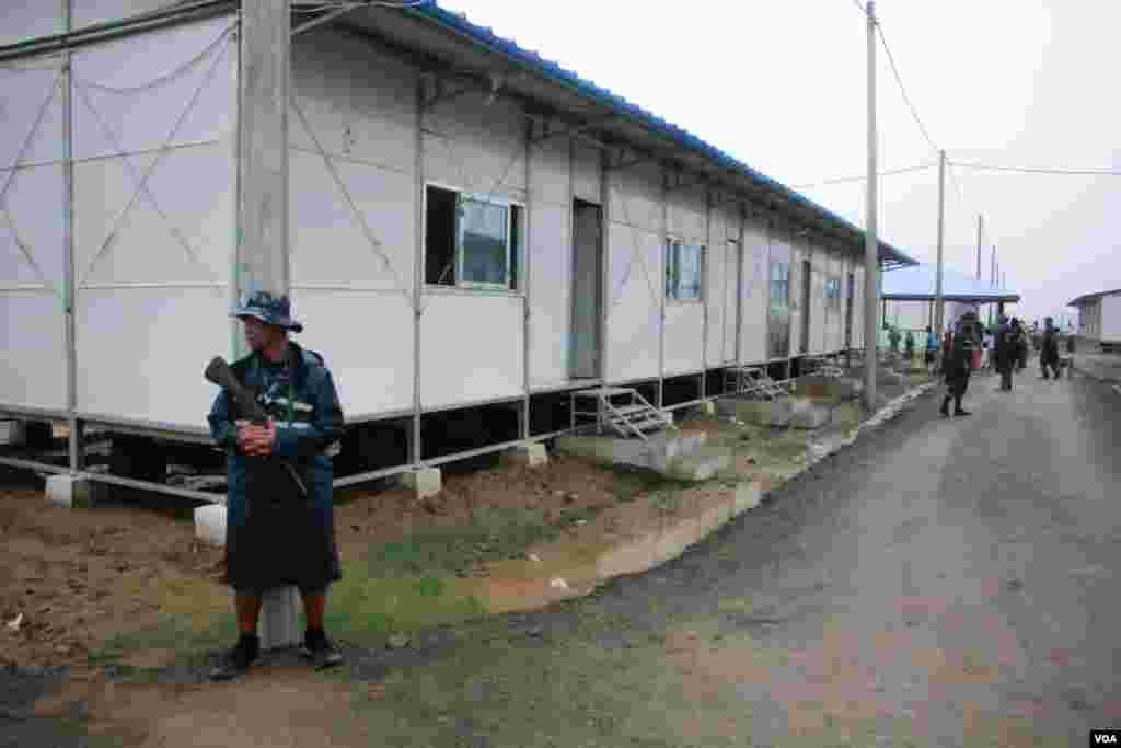 မလေးရှားဘက်ထွက်ပြေးရာက လှေမှောက်ခဲ့တဲ့ ဒုက္ခသည် ၁၀၄ ဦးကို မြန်မာအစိုးရအာဏာပိုင်များက စောင့်ရှာက်ထားရာ အဆောက်အဦးရှေ့မှာ တာဝန်ယူနေတဲ့ ရဲတပ်ဖွဲ့ဝင်တဦး။ (ဓာတ်ပုံ-ထက်အောင်ခန့့်)