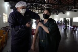 Captain Jackeline Guillen gets a shot of the Pfizer COVID-19 vaccine from an Health Ministry worker at a military barracks in Mariano Roque Alonso, Paraguay, July 12, 2021.