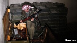 Một chiến binh phe nổi dậy xem các võ khí tịch thu được tai một căn cứ quân sự ở làng Hawa, nằm về hướng bắc thành phố Aleppo, 23/12/12